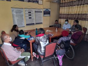 10 people seated around a table in a hall, discussing with each other
