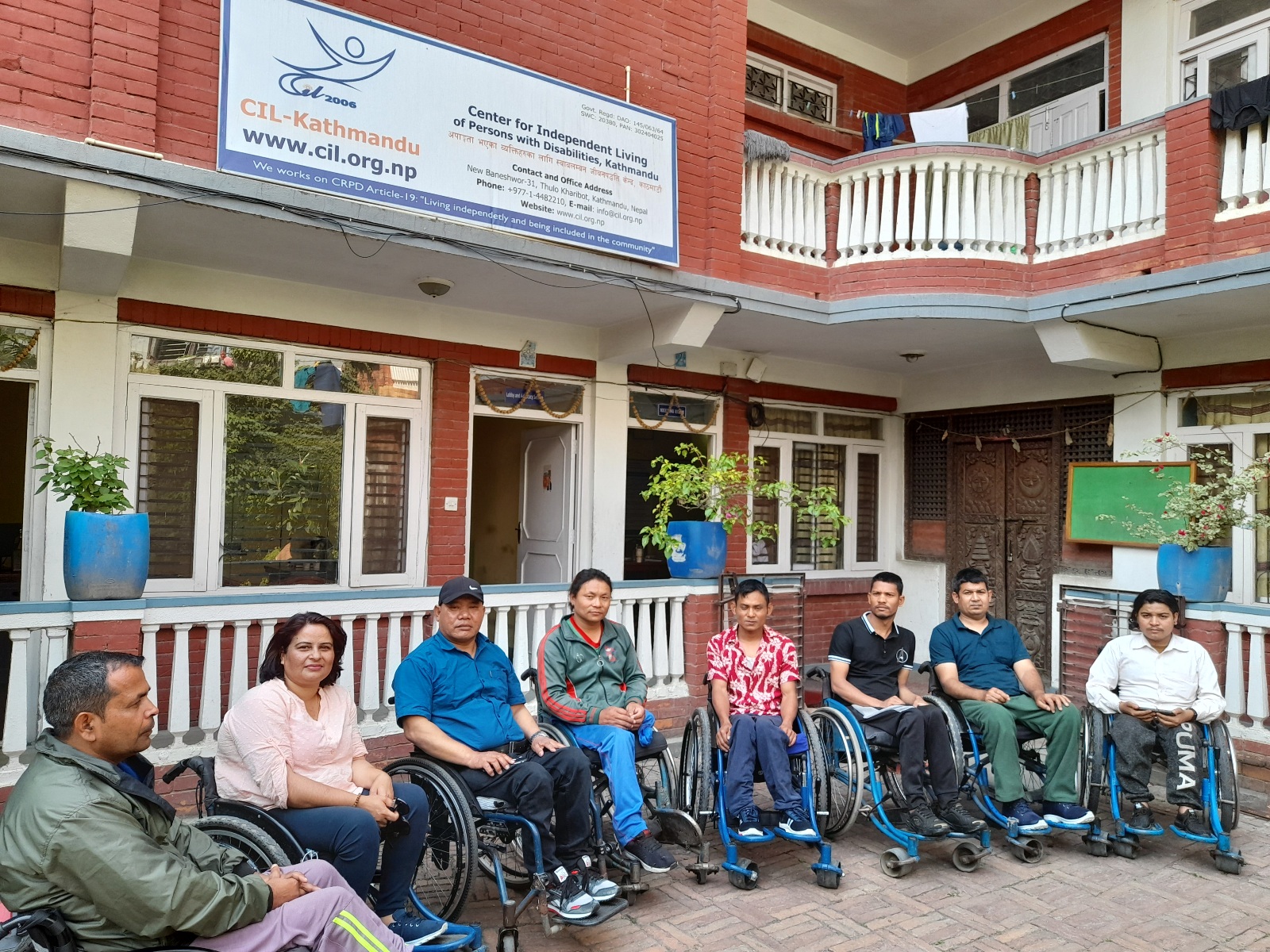 people using wheelchair are lined in a row in the yard for the photo